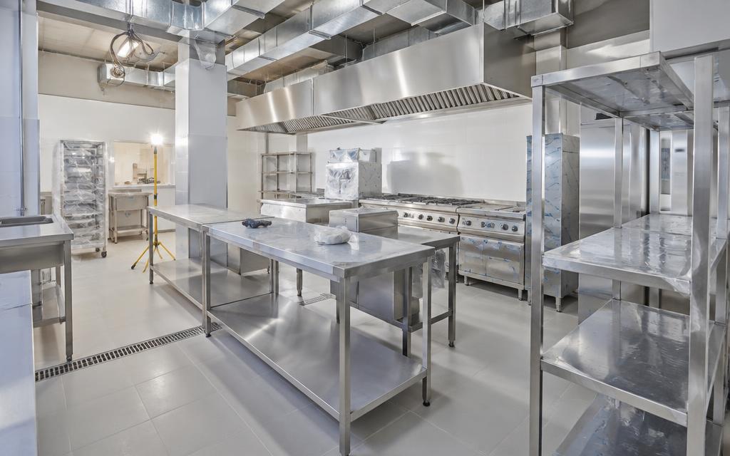 Commercial kitchen half way through fit-out with new stainless steel worktables and extraction hood