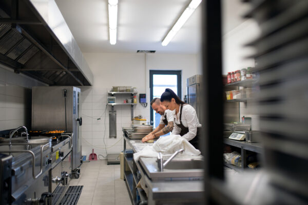 A chef and cook working on their dishes indoors in restaurant kitchen.